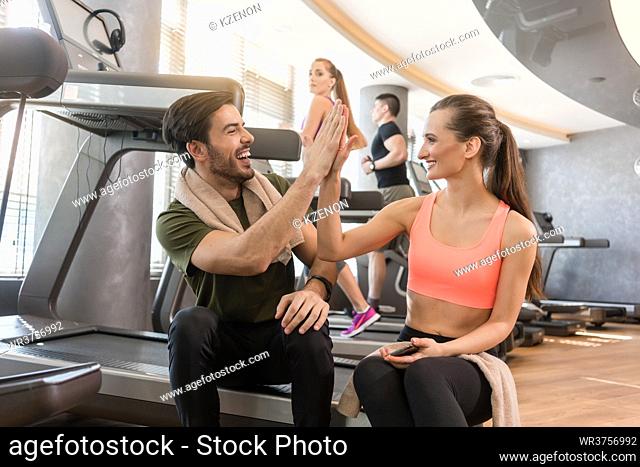 Cheerful young man and woman giving high five after a successful workout session in a modern fitness club