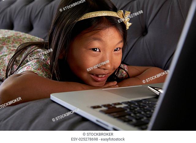 Girl Relaxing On Sofa At Home Using Laptop