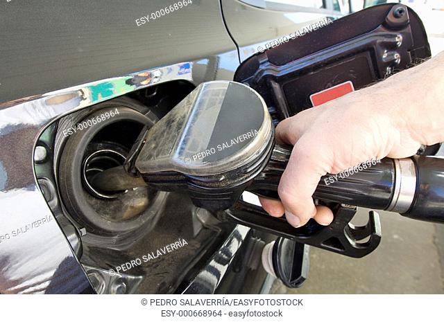 Hand holding fuel pump refueling a car