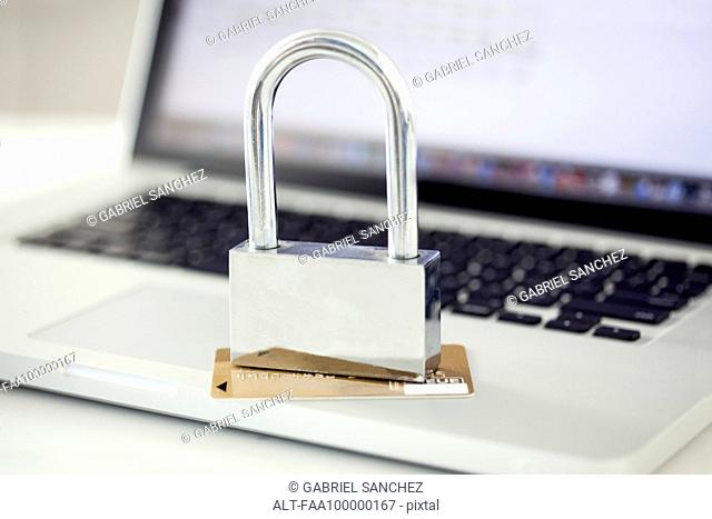 Padlock and credit card sitting on top of laptop computer