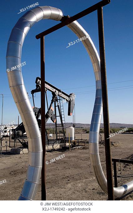 Taft, California - An expansion loop in a natural gas pipeline frames an oil well in the oil and gas fields of southern San Joaquin Valley