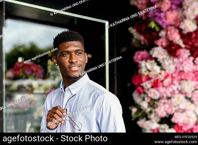 Young man with eyeglasses outside flower shop