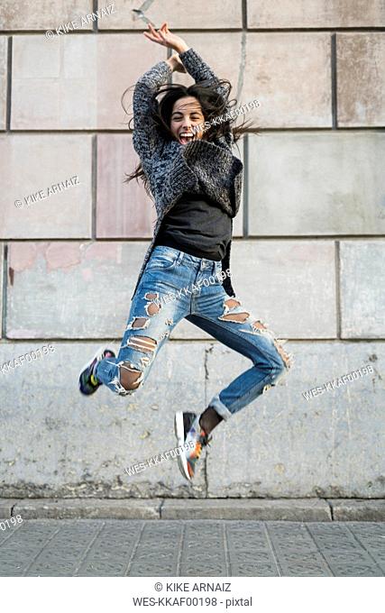 Portrait of exuberant young woman jumping around