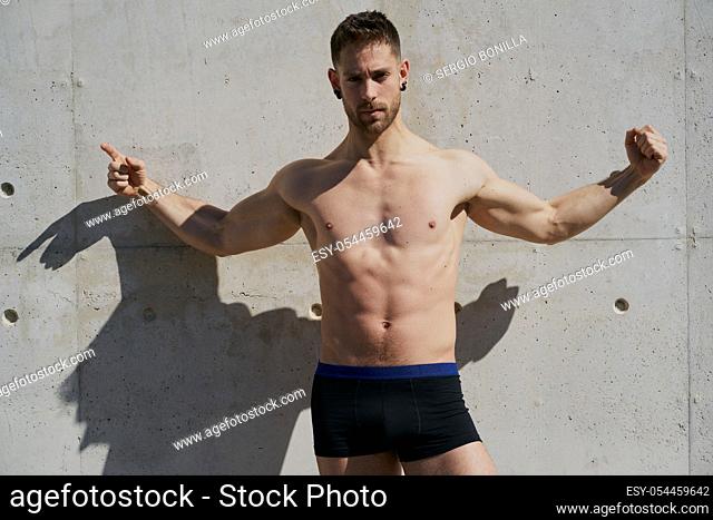 Portrait of a pretty guy dressed in boxers on a concrete wall