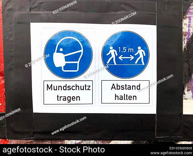 wear face mask and keep distance sign with (german: Mundschutz tragen - Abstand halten )