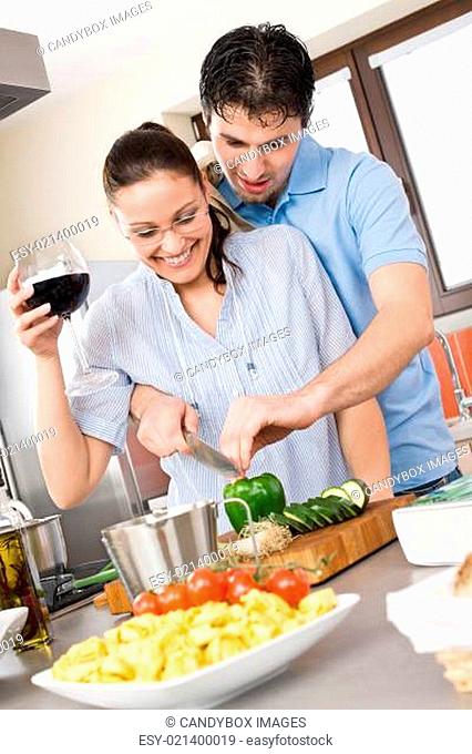Happy couple cut vegetables in kitchen