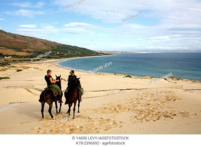 People riding horses on the dune of Ensenada de Valdvaqueros with a view over Playa de los Lances beach, Tarifa, Andalucia, Spain