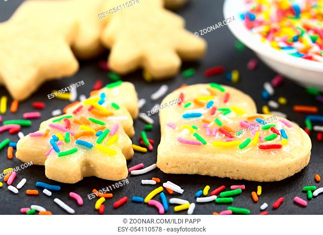 Homemade baked sugar cookies for Christmas with icing and colorful sprinkles on the top (Selective Focus, Focus one third into the image)