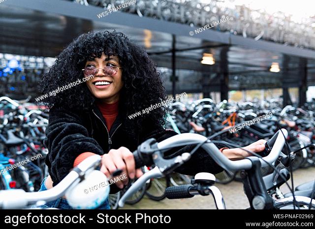 Smiling young woman at bicycle parking station