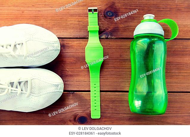 sport, fitness, healthy lifestyle and objects concept - close up of sneakers, bracelet and water bottle on wooden floor