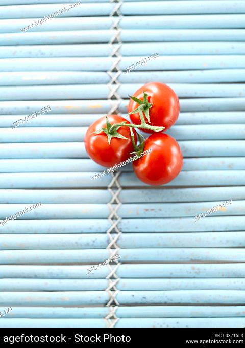 Three tomatoes on blue mat