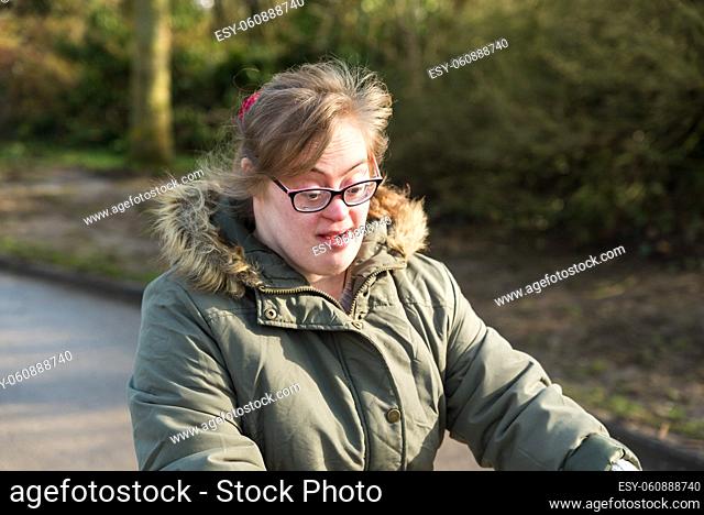 Tienen, Flanders / Belgium - 07 20 2018: Portrait of a young white woman with Down Syndrome driving a tricycle through the fields