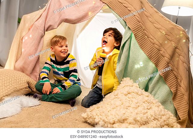 happy boys with torch light in kids tent at home