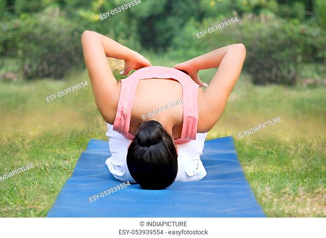 Young woman in lawn doing yoga