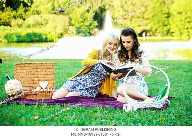 Two women reading book in the colorful park
