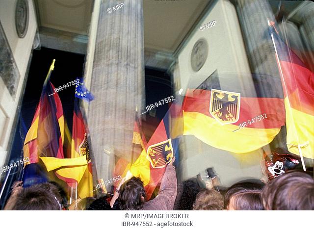 German flags, citizens of Berlin celebrating the reunion of East and West Germany in front of the Brandenburger Tor at night, DDR, October 3rd 1990, Berlin