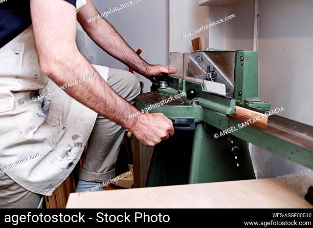 Mature craftsman using machinery while working in workshop