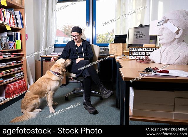 PRODUCTION - 24 October 2022, Saxony, Dresden: Anja Besand, an educationalist, sits in her office at the TU Dresden next to her golden retriever Sidan