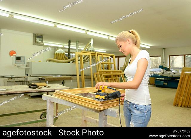 Young woman in a carpentry working on a window frame