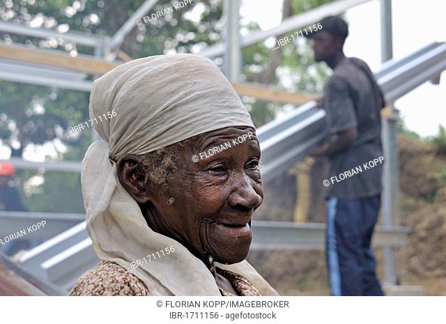 Old woman, victim of the January 2010 earthquake, is watching the construction of her new home, she is receiving an earthquake-proof prefab house from an...