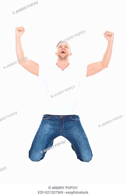 Excited man cheering in jubilation dropping down on his knees