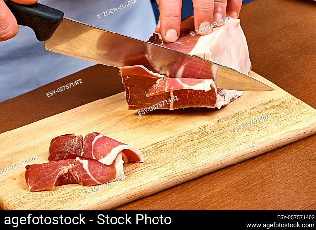Dry cured ham thinly sliced Closeup on chef hands slices prosciutto Italian delicatessen dishes cooking process