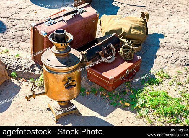 Vintage travel luggage with old suitcases and copper samovar in sunny day