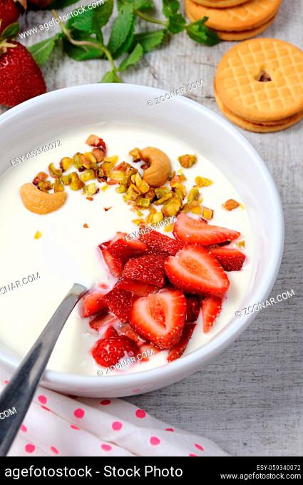 Chilled Buttermilk soup from Greek yogurt with strawberries and pistachios, cashews. Serve with crispy biscuits. Vertical shot