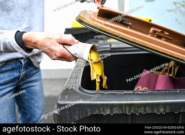 24 March 2023, Baden-Württemberg, Ravensburg: A woman throws banana peels wrapped in newspaper into a garbage can for organic waste