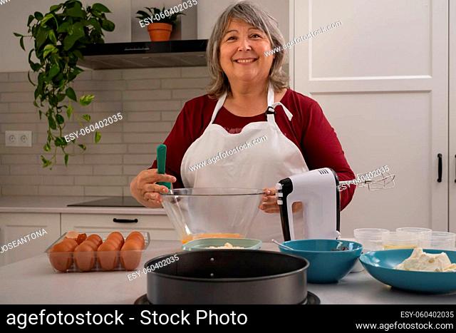 older woman with white hair making a strawberry cake in her home kitchen