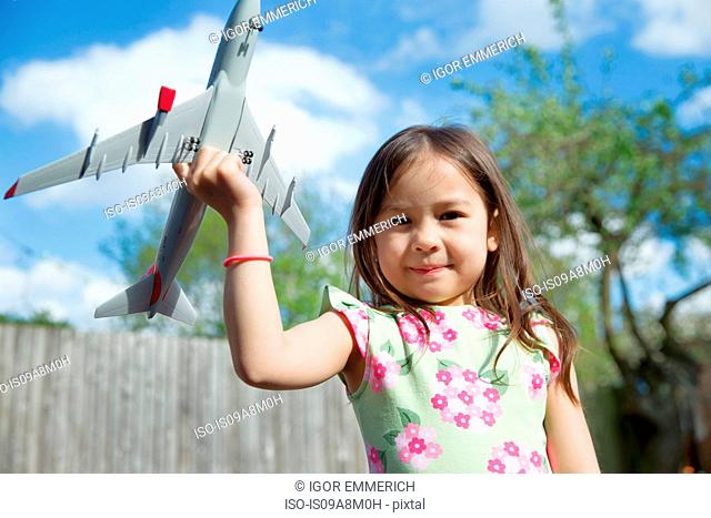 Portrait of young girl in garden holding toy airplane