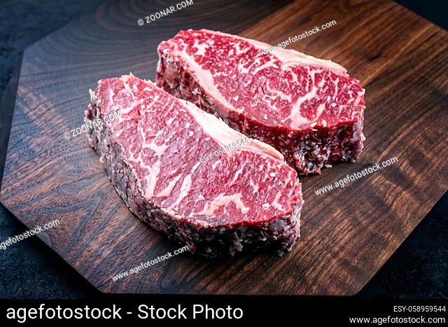 Modern style raw dry aged wagyu roast beef steak offered as top view on a wooden design board