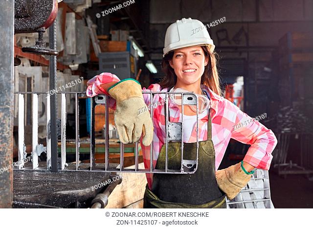 Junge Frau als stolzer Lehrling mit Gussform in einem Betrieb für Metallverarbeitung