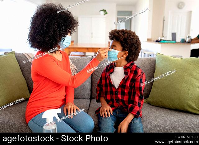Mother putting face mask on her son at home