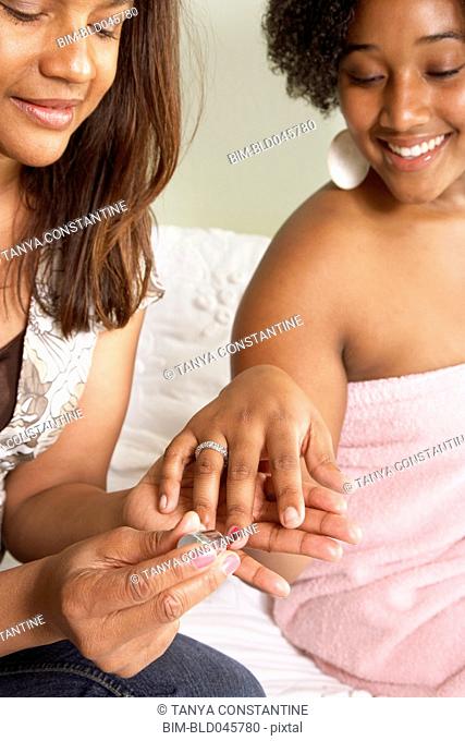 African American mother painting daughter's fingernails