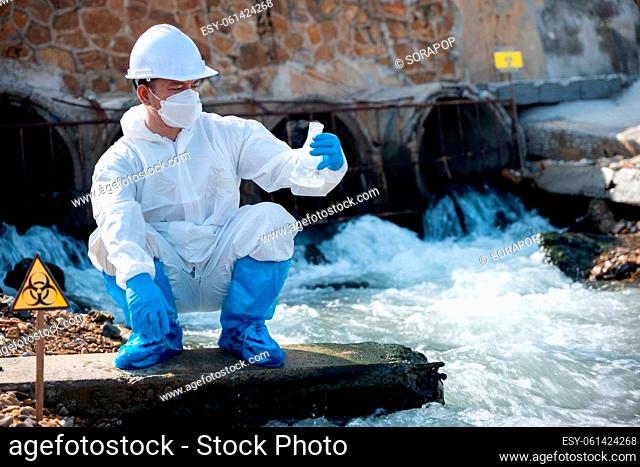 Ecologist sampling water from river with test tube glass and have white smoke, Biologist collects sample waste water from industrial of toxic chemicals