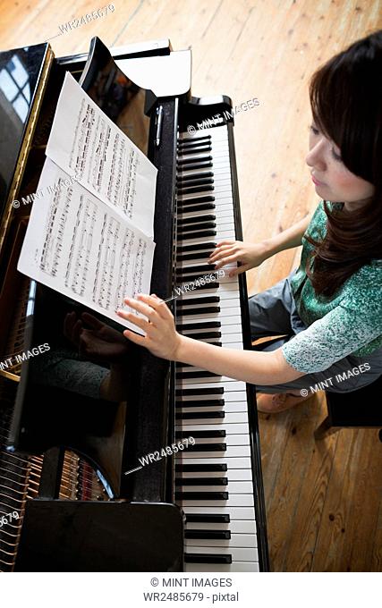 Young woman playing on a grand piano in a rehearsal studio