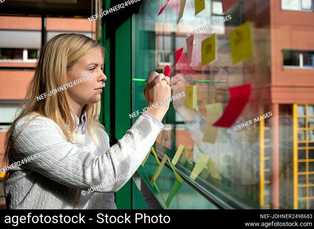 Woman making notes on post it sticker to window