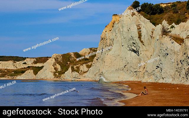 greece, greek islands, ionian islands, kefalonia, xi beach, red sands rocks white, sky blue, a woman sits alone on the beach