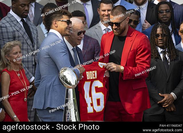 Kansas City Chiefs quarterback Patrick Mahomes(light blue suit) and tight end Travis Kelce(red suit) present United States President Joe Biden with a team...