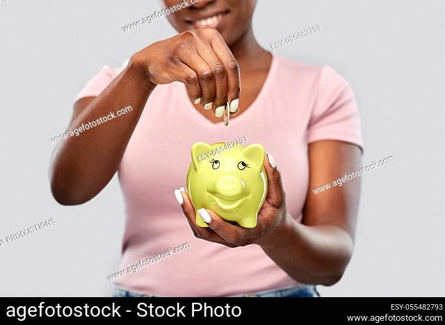 close up of woman with coin and piggy bank