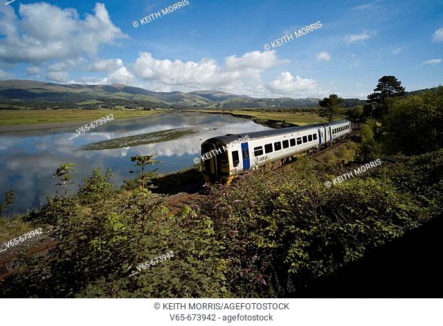 Arriva Trains Wales diesel train at Dovey Junction near Machynlleth Powys, with the Dyfi River behind and the hills and mountains of Snowdonia National Park in...