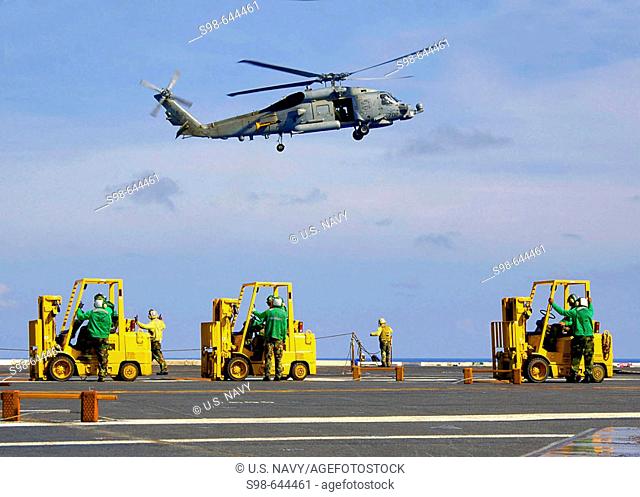Pacific Ocean (May 19, 2006) - Forklift operators watch as a SH-60B Seahawk assigned to the Saberhawks of Helicopter Anti-submarine Squadron Light Four Seven...