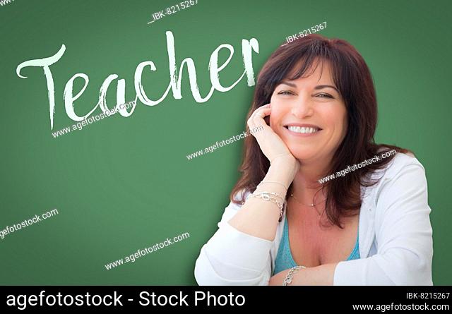 Teacher written on green chalkboard behind smiling middle aged woman