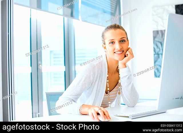 Attractive young woman sitting at desk and working on her computer