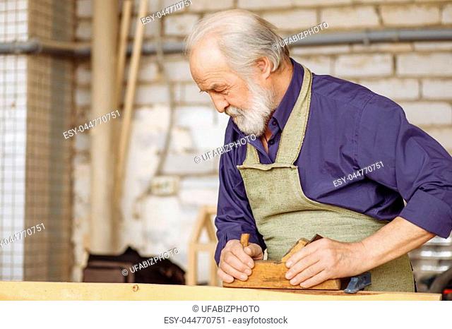 close up side view shot of strong pensioner shaping wood