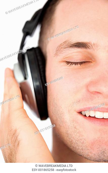 Close up of a serene man listening to music against a white background