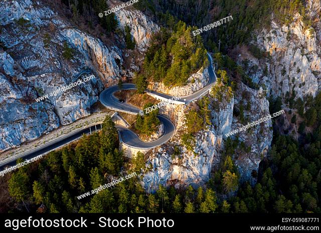 curve road on the mountain with green forest during autumn in austria - aerial view