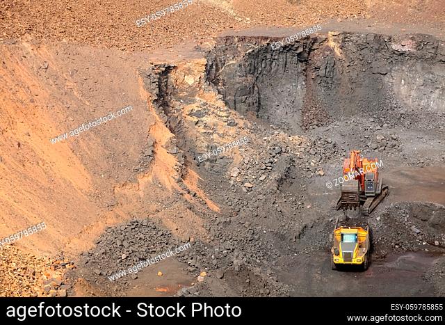 Open pit Manganese Mining - Excavator digging out ore rich rock and loading it onto rock dump trucks for processing