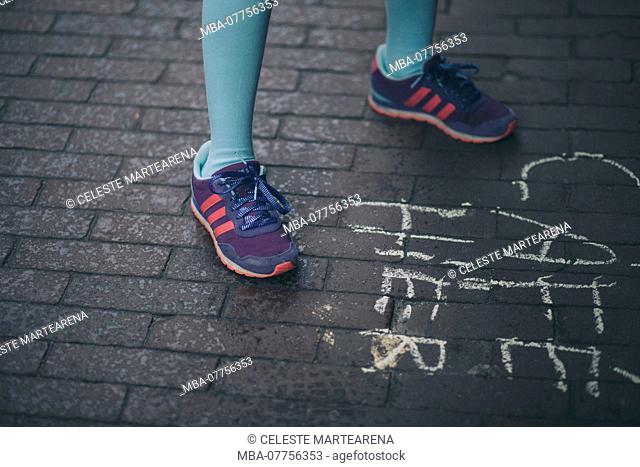 legs of a little girl stepping on some bricks floor with colorful sneakers